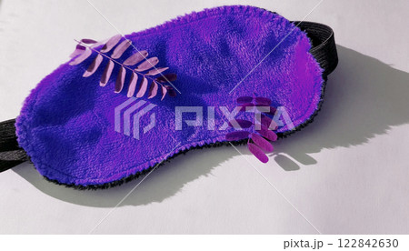 Camera movement over a soft orange eye mask lying in the morning on a white background with twigs of plants, top view. Healthy sleep concept 122842630