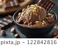 Chocolate ice cream with gold leaf, hazelnuts and chocolate bar melting in a black bowl 122842816