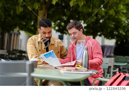 Special educator using multi sensory teaching methods with young man with Down syndrome. 122843206