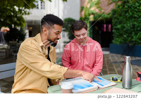 Special educator using multi sensory teaching methods with young man with Down syndrome. 122843207