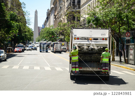 A large garbage truck is driving along a busy city street today A large garbage truck is driving along a busy city street today 122843981