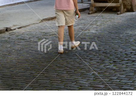 A person is leisurely walking down a charming cobblestone street A person is leisurely walking down a charming cobblestone street 122844172