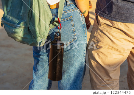 The girl has a water bottle on her belt. plastic thermos for drinking water in the steppe 122844476