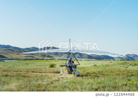 hang glider takeoff in the Kazakh steppe. light aircraft with a pilot and passenger hang glider takeoff in the Kazakh steppe. light aircraft with a pilot and passenger 122844488