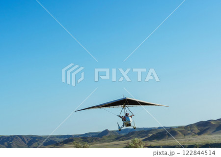 Hang glider for riding tourists in the field. Two-seater hang glider flying in the sky 122844514