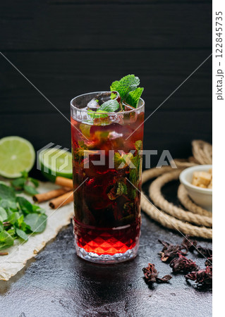 Refreshing hibiscus cocktail with lime, mint, and ice in a tall glass, summer and tropical vibes 122845735