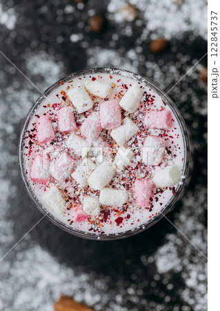 Cup of pink hot chocolate with marshmallows and powdered sugar on a rustic dark background 122845737