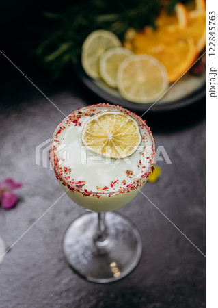 Elegant citrus cocktail in tall glass with floral garnish and dried lime slice, perfect for summer 122845763