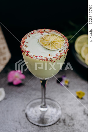 Elegant citrus cocktail in tall glass with floral garnish and dried lime slice, perfect for summer Elegant citrus cocktail in tall glass with floral garnish and dried lime slice, perfect for summer 122845769