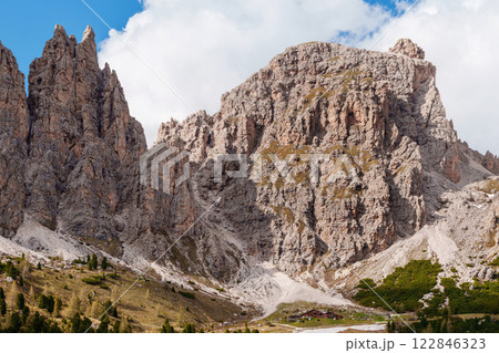 Majestic mountain range with rocky peaks and lush valley beneath blue sky near Valley of Funes at Dolomites, Italy 122846323