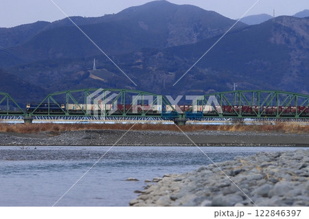 お茶畑が並ぶ山々を背景に大井川を渡るEF65形電気機関車牽引の貨物列車_2025/1/12撮影 122846397