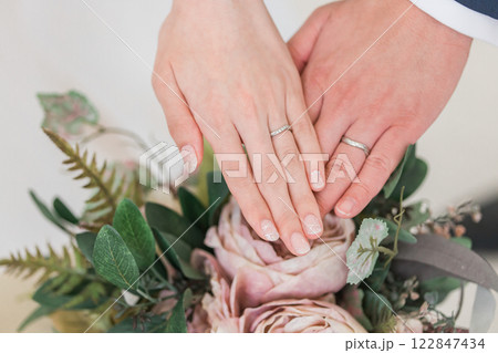 結婚指輪・マリッジリングをする新郎新婦の手とブーケ 122847434
