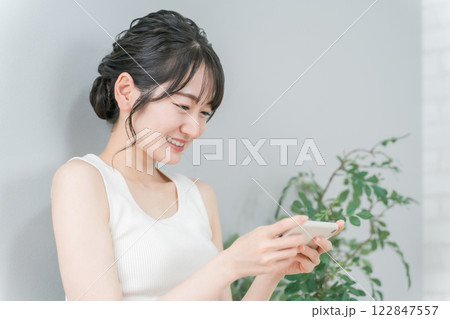 家で動画を見る・スマホゲームをするリラックスしたアジア人女性 122847557