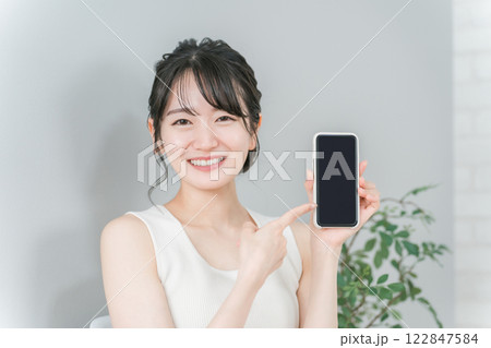 スマホの画面を指差す笑顔のアジア人女性 スマホの画面を指差す笑顔のアジア人女性 122847584