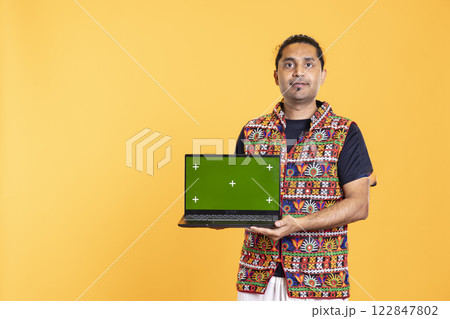 Portrait of smiling man holding green screen laptop, doing important work for company, isolated over studio background. Employee with mockup on notebook device, isolated over studio backdrop Portrait of smiling man holding green screen laptop, doing important work for company, isolated over studio background. Employee with mockup on notebook device, isolated over studio backdrop 122847802