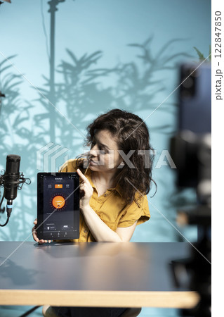 Influencer in studio doing affiliate marketing, advertising smart light controlling tablet application for online streaming platforms. Content creator promoting IoT home automation product tech Influencer in studio doing affiliate marketing, advertising smart light controlling tablet application for online streaming platforms. Content creator promoting IoT home automation product tech 122847850