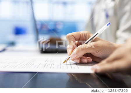 Skilled doctor writing down options and plans for recovery treatment, consulting with his colleagues in a meeting after seeing x ray test results. Examining records and scans for diagnosis. Close up. 122847896