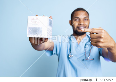 Portrait of dermatologist talking about refreshing aloe vera gel, standing against blue background. Skincare expert recommending detox anti inflammatory beauty moisturizer, organic lotion. 122847897