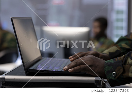 IT professional operating laptop to gather important information from cctv satellite systems, control tower tasks. Collecting real time data for security measures and national interests. Close up. 122847898