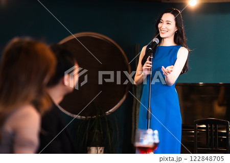 ライブ演奏がある飲食店で歌う若い女性とお客様 122848705