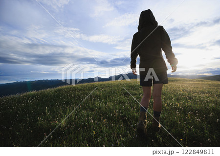 Woman hiker walking beautiful flowering grassland Woman hiker walking beautiful flowering grassland 122849811