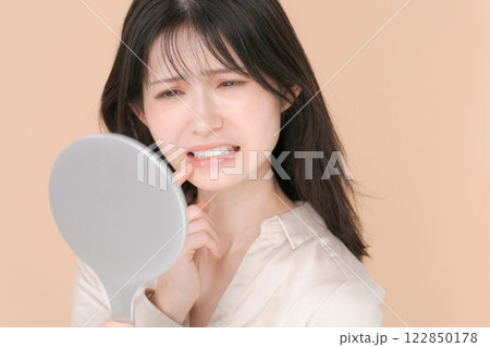 鏡を見て困った表情をする20代女性 鏡を見て困った表情をする20代女性 122850178