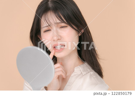 鏡を見て困った表情をする20代女性 122850179