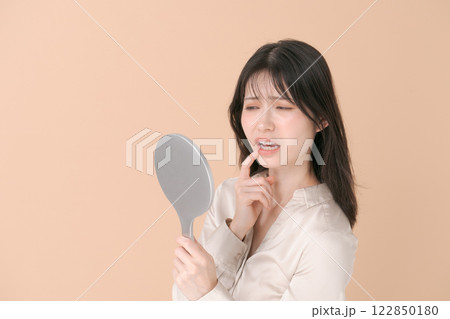 鏡を見て困った表情をする20代女性 鏡を見て困った表情をする20代女性 122850180