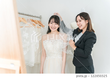 鏡を見ながら結婚式のウェディングドレス・ベールの衣装合わせ・試着をする花嫁 122850325