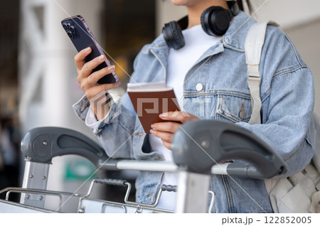 A close-up of a female traveler is waiting for her taxi at an airport pickup point. 122852005