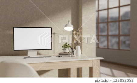 A computer and decorative items on a desk, set against a wall in a minimalist room. 122852058