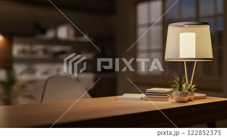 A hardwood desk with decorative items and a lamp, creating a warm atmosphere in the room at night. 122852375
