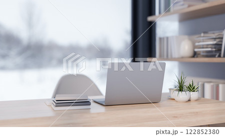 A back view of a laptop placed on a desk in a modern office with a overlooking a snowy winter view. A back view of a laptop placed on a desk in a modern office with a overlooking a snowy winter view. 122852380