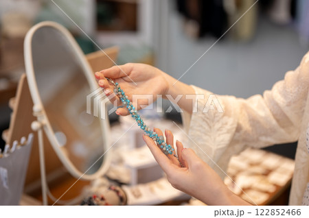 A close-up of a female customer holding a bracelet, selecting items to buy in a fashion shop. A close-up of a female customer holding a bracelet, selecting items to buy in a fashion shop. 122852466
