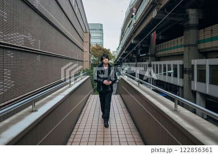 歩道橋を歩く黒いジャンバーを着た男性のポートレート 122856361