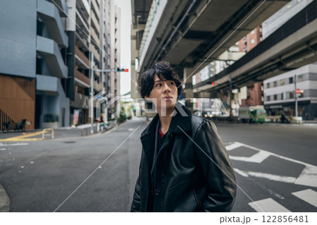 街を歩く黒いジャンバーを着た男性のポートレート 街を歩く黒いジャンバーを着た男性のポートレート 122856481