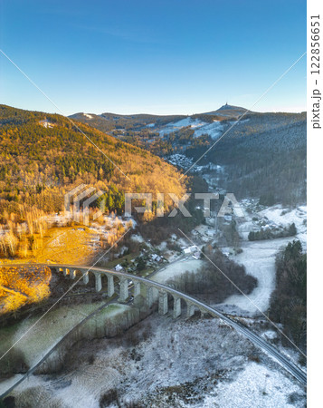 The railway stone bridge in Novina spans across a serene valley, illuminated by the warm hues of a winter sunset. 122856651