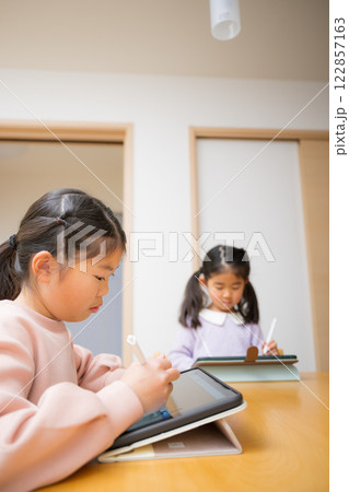 逆光の中、勉強や宿題をみるお母さんや塾の先生 小学生低学年の笑顔の子供「タブレットでも勉強楽しい」 逆光の中、勉強や宿題をみるお母さんや塾の先生 小学生低学年の笑顔の子供「タブレットでも勉強楽しい」 122857163