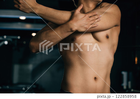 Asian man stretching arms for bodybuilder fitness in gym interior, male holding muscle warm up before training at fitness gym, sport workout healthy lifestyle concept Asian man stretching arms for bodybuilder fitness in gym interior, male holding muscle warm up before training at fitness gym, sport workout healthy lifestyle concept 122858958