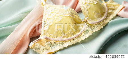 Delicate Yellow Lace Lingerie with Pink Trim Details on Soft Pastel Silk Background 122859071