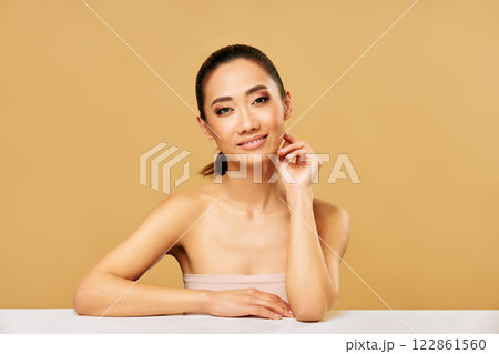 Beauty portrait of smiling young woman with healthy skin posing over beige background. 122861560