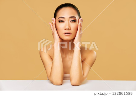 Beautiful young woman with with healthy skin and natural makeup posing against beige background 122861589