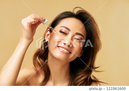 Happy smiling woman applying facial serum using pipette dropper. Moisturising and nourishing. Happy smiling woman applying facial serum using pipette dropper. Moisturising and nourishing. 122861600