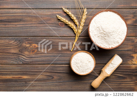 Flat lay of Wheat flour in wooden bowl with wheat spikelets on colored background. world wheat crisis 122862662