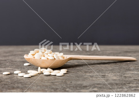 Heap of white pills on colored background. Tablets scattered on a table. Pile of red soft gelatin capsule. Vitamins and dietary supplements concept Heap of white pills on colored background. Tablets scattered on a table. Pile of red soft gelatin capsule. Vitamins and dietary supplements concept 122862862