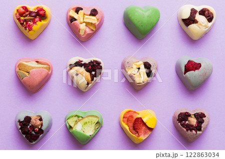 chocolate sweets in the form of a heart with fruits and nuts on a colored background. top view with space for text, holiday concept 122863034