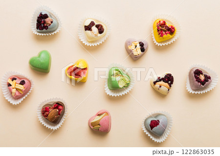 chocolate sweets in the form of a heart with fruits and nuts on a colored background. top view with space for text, holiday concept 122863035
