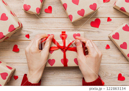 Women hands pack gifts and make decorations for the holiday, top view. Birthday and valentine present Women hands pack gifts and make decorations for the holiday, top view. Birthday and valentine present 122863134