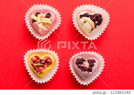 chocolate sweets in the form of a heart with fruits and nuts on a colored background. top view with space for text, holiday concept 122863148