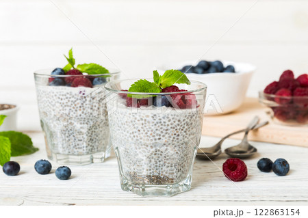 Healthy breakfast or morning with chia seeds vanilla pudding raspberry and blueberry berries on table background, vegetarian food, diet and health concept. Chia pudding with raspberry and blueberry 122863154